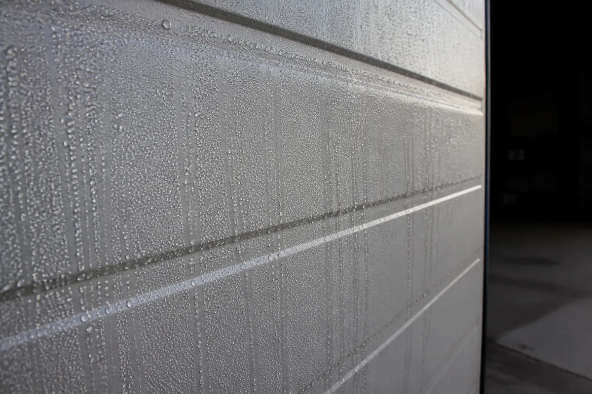Porte de garage métallique couverte de gouttelettes de condensation un matin d’hiver