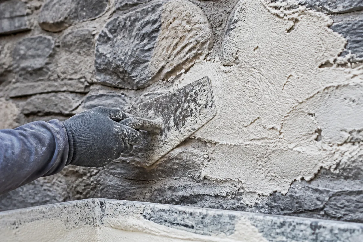 Truelle appliquant un enduit de chaux frais sur une maçonnerie de pierre